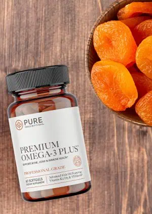 Premium Omega-3 Plus flatlay beside a bowl of apricots.