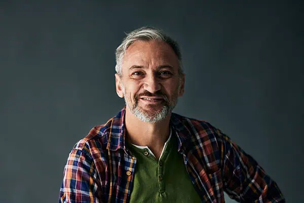 Grey-haired mature man, smiling for the camera, isolated on the grey background.